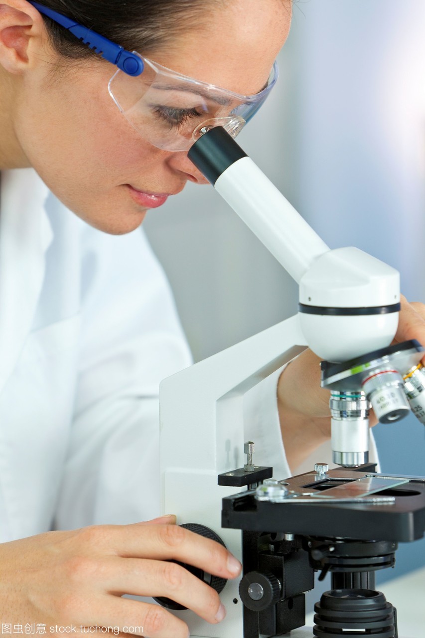 一个美丽的女性医学或科学研究人员使用显微镜在实验室。